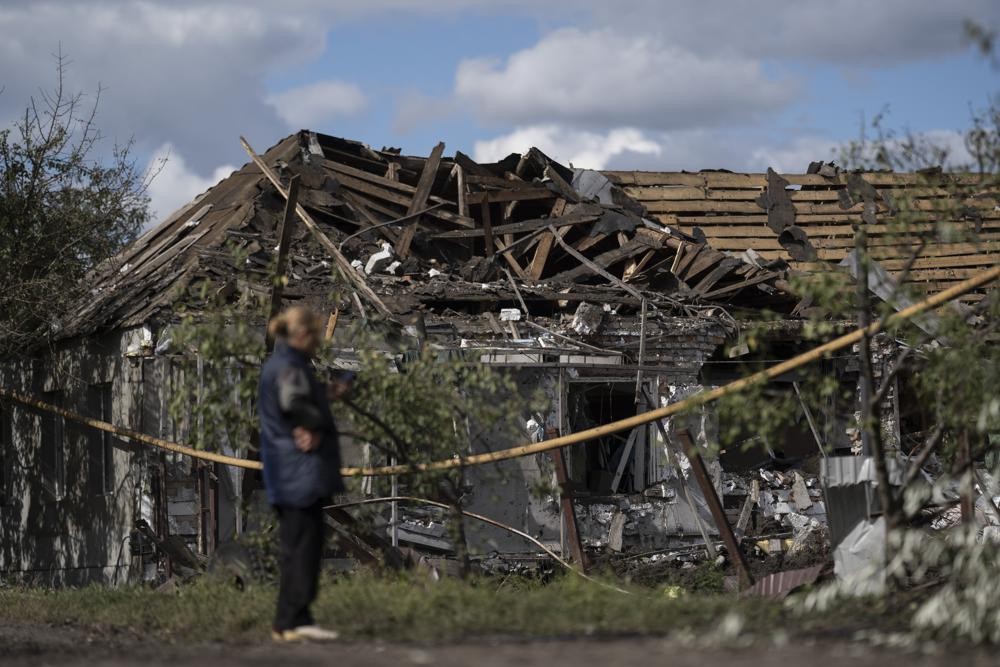FILE - A woman stands in front of a house that was heavily damaged after a Russian attack in Sloviansk, Ukraine, on Sept. 6, 2022. It's at night that residents of the eastern Ukrainian city of Sloviansk are most afraid, when rocket and artillery attacks happen more frequently. Shells and rockets slam into gardens and apartment buildings, sending chunks of masonry and shards of glass hurtling through the darkness. (AP Photo/Leo Correa, File)